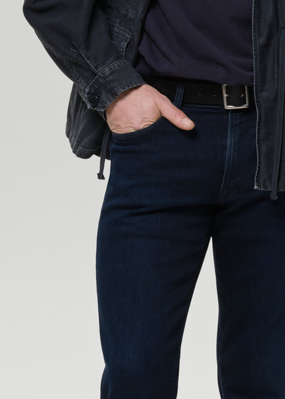 Person wearing dark blue jeans with a grey background