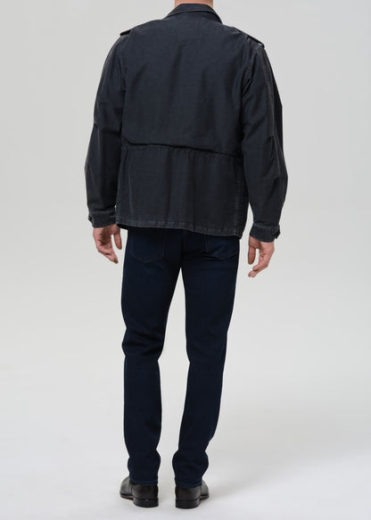 Person wearing a dark jacket and pants on a grey background