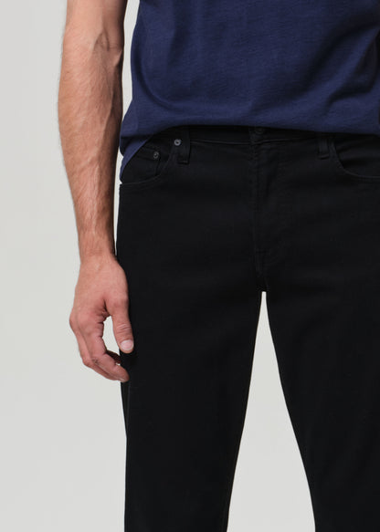 Person wearing a navy blue t-shirt and black jeans on a grey background