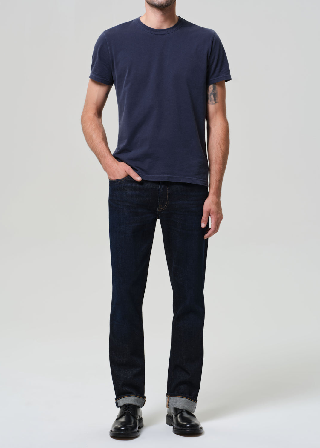 Person wearing a navy t-shirt and dark jeans on a plain background