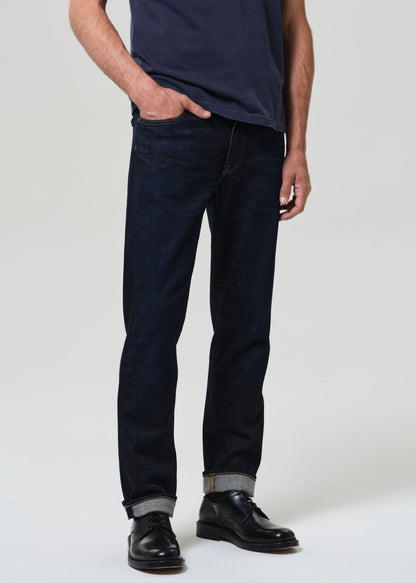 Person wearing dark blue jeans and black shoes on a white background