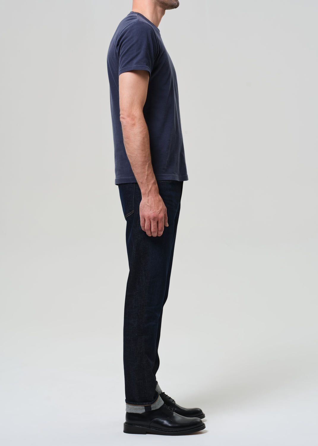 Person wearing a navy t-shirt and dark pants on a white background