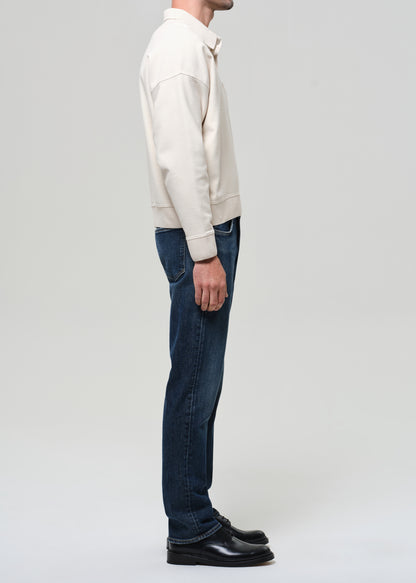 Person wearing a cream sweater and dark jeans on a white background