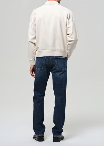 Person wearing a beige jacket and blue jeans on a white background