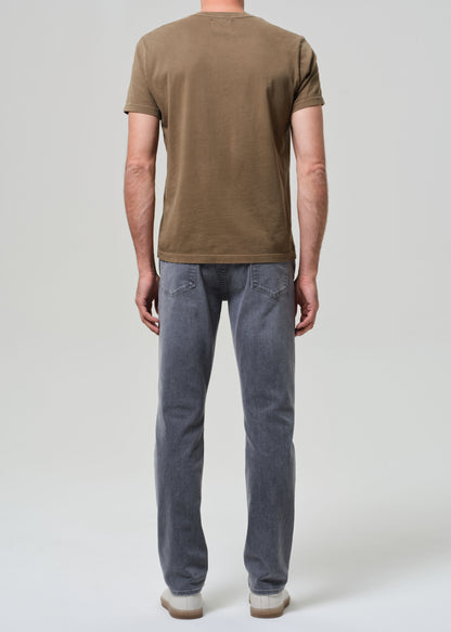 Person wearing a brown t-shirt and gray jeans on a grey background