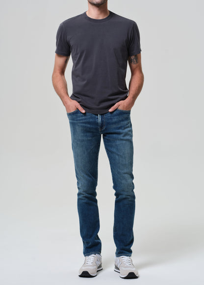 Person wearing a dark gray t-shirt and blue jeans on a white background
