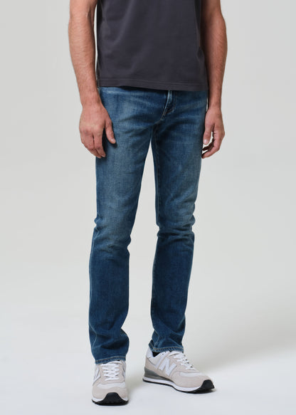 Person wearing blue jeans and white sneakers on a plain background