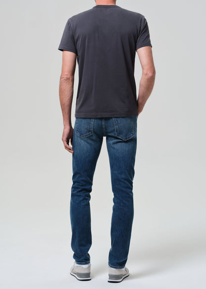 Person wearing a dark gray t-shirt and blue jeans on a white background