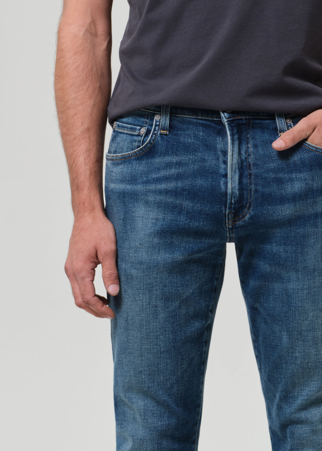 Person wearing blue jeans and a dark shirt on a plain background