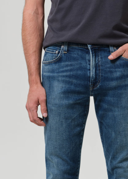 Person wearing blue jeans and a dark shirt on a plain background