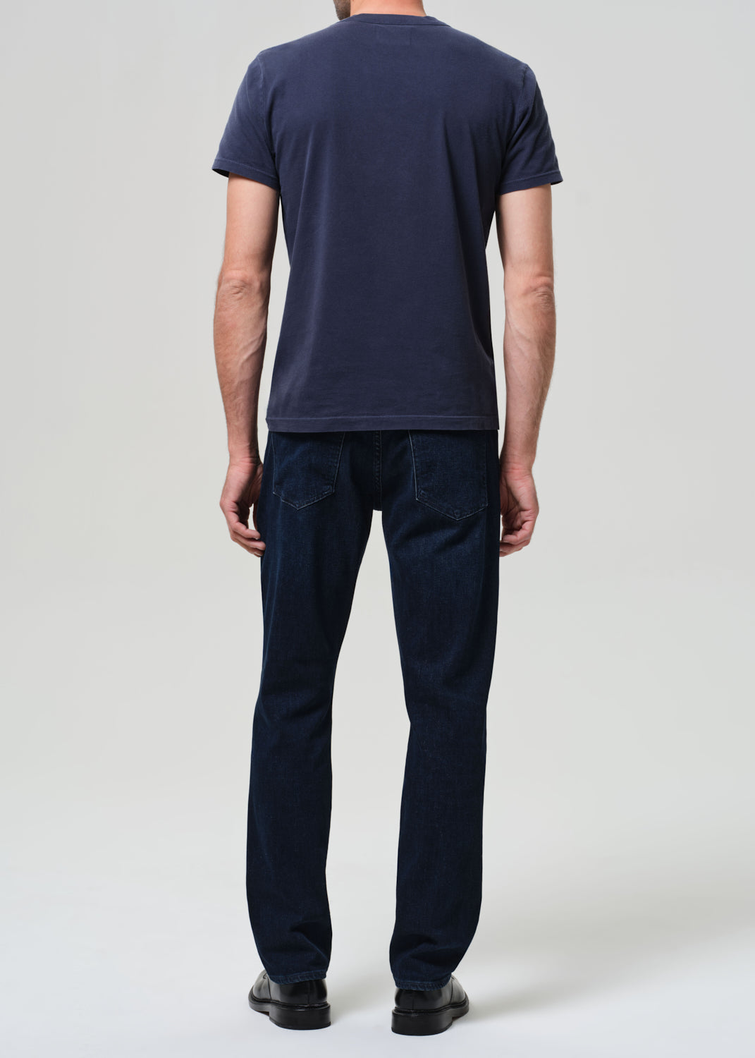 Person wearing a navy t-shirt and dark jeans 