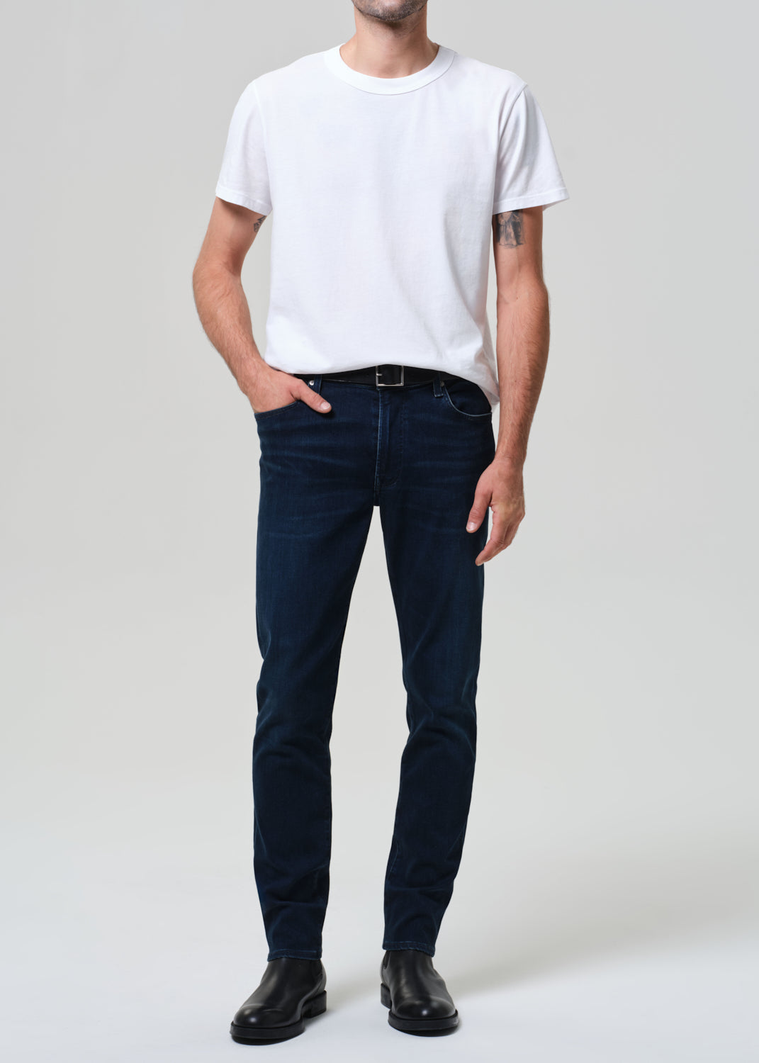 Person wearing a white t-shirt and dark jeans