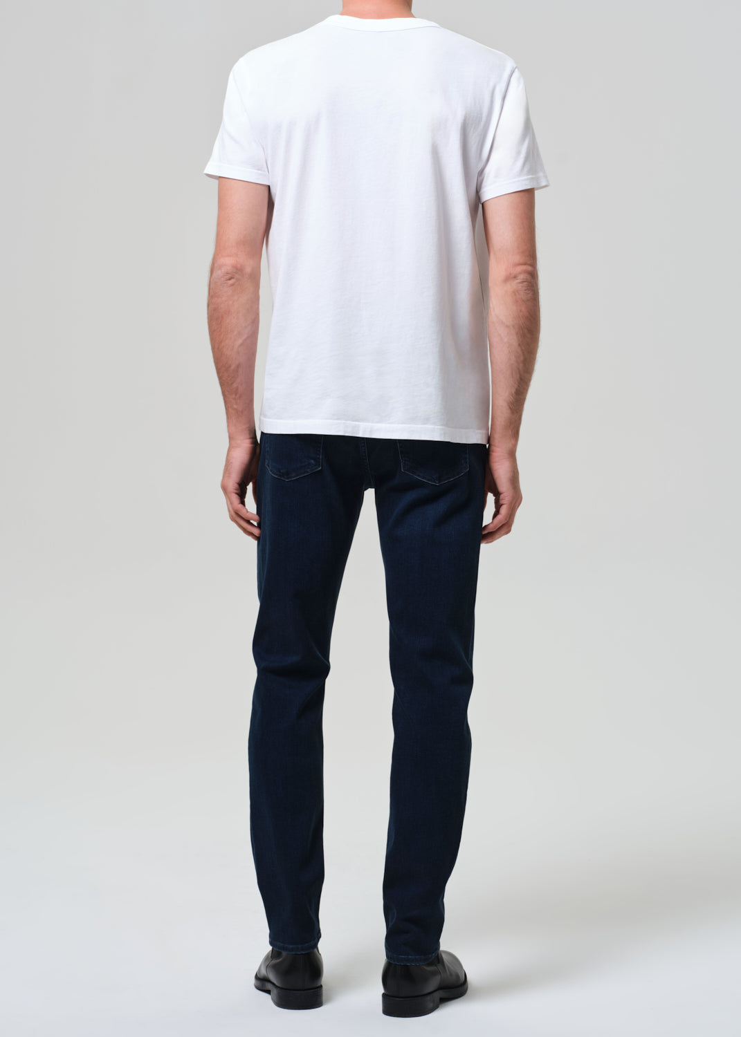 Person wearing a white t-shirt and dark jeans