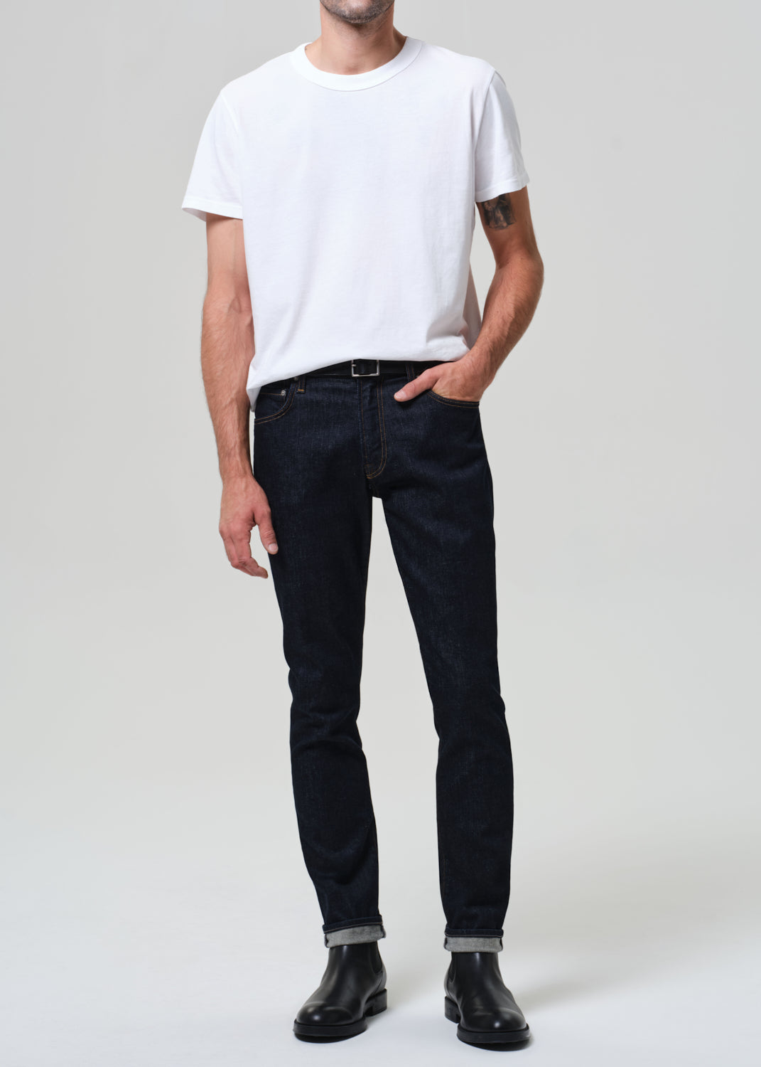 Person wearing a white t-shirt and black jeans on a plain background