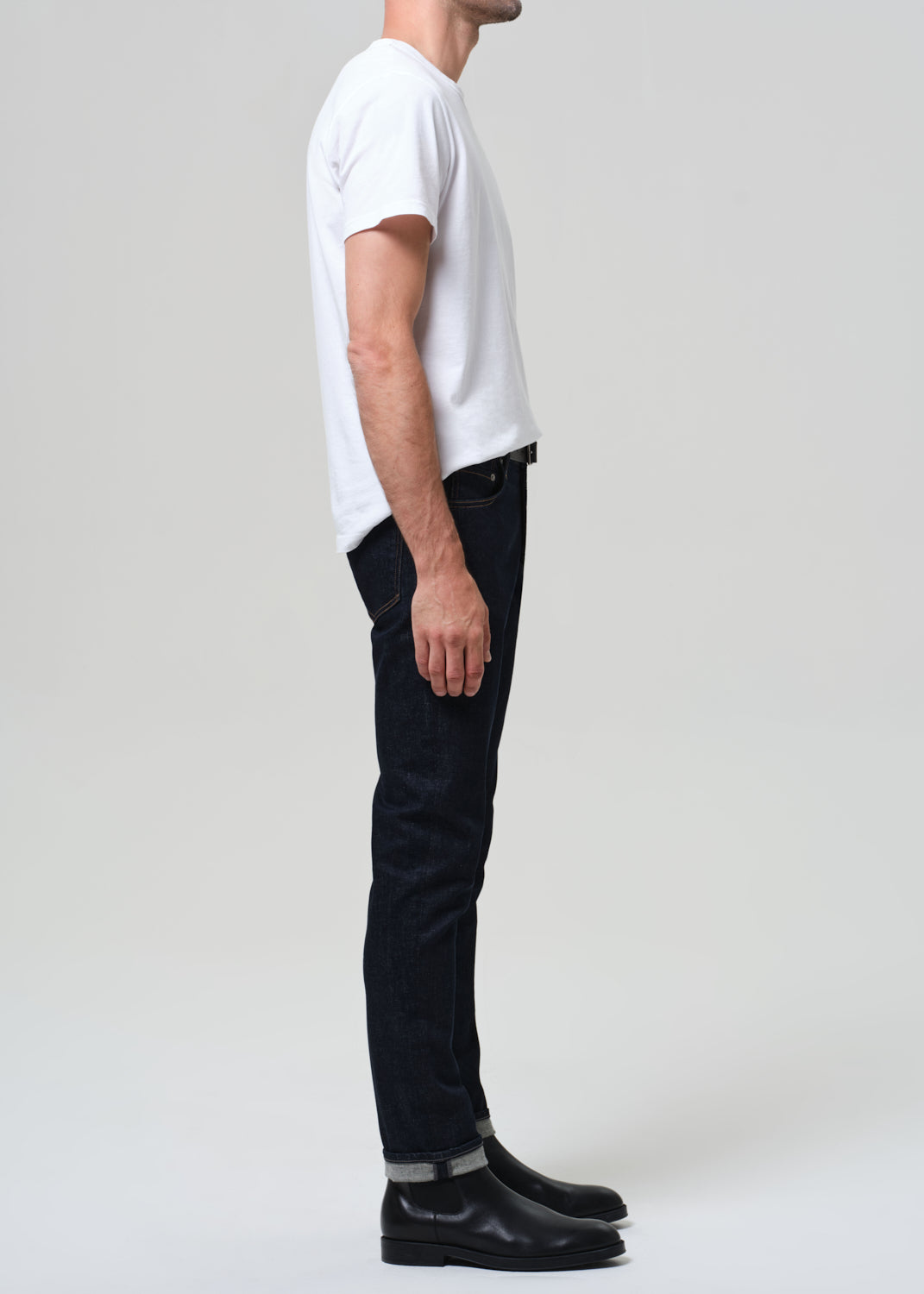 Person wearing a white t-shirt and black jeans on a plain background