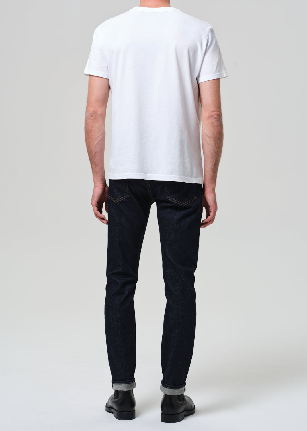 Person wearing a white t-shirt and black pants on a plain background