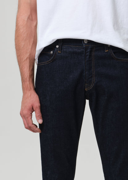 Person wearing dark blue jeans and a white shirt on a light gray background