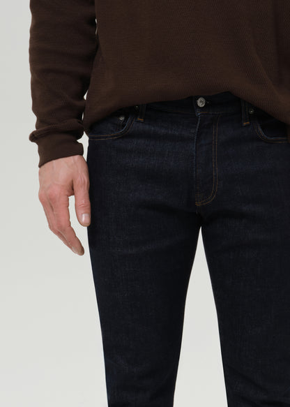 Close-up of dark indigo straight leg jeans on a grey background.