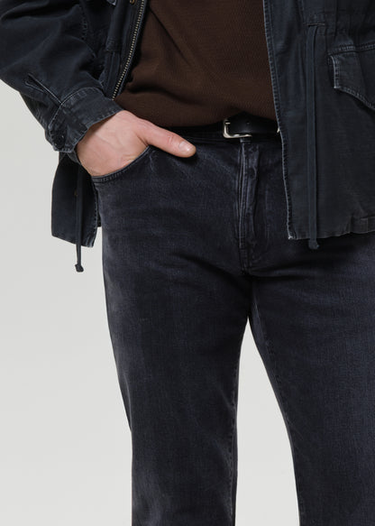 Close-up of dark indigo straight leg jeans on a grey background.