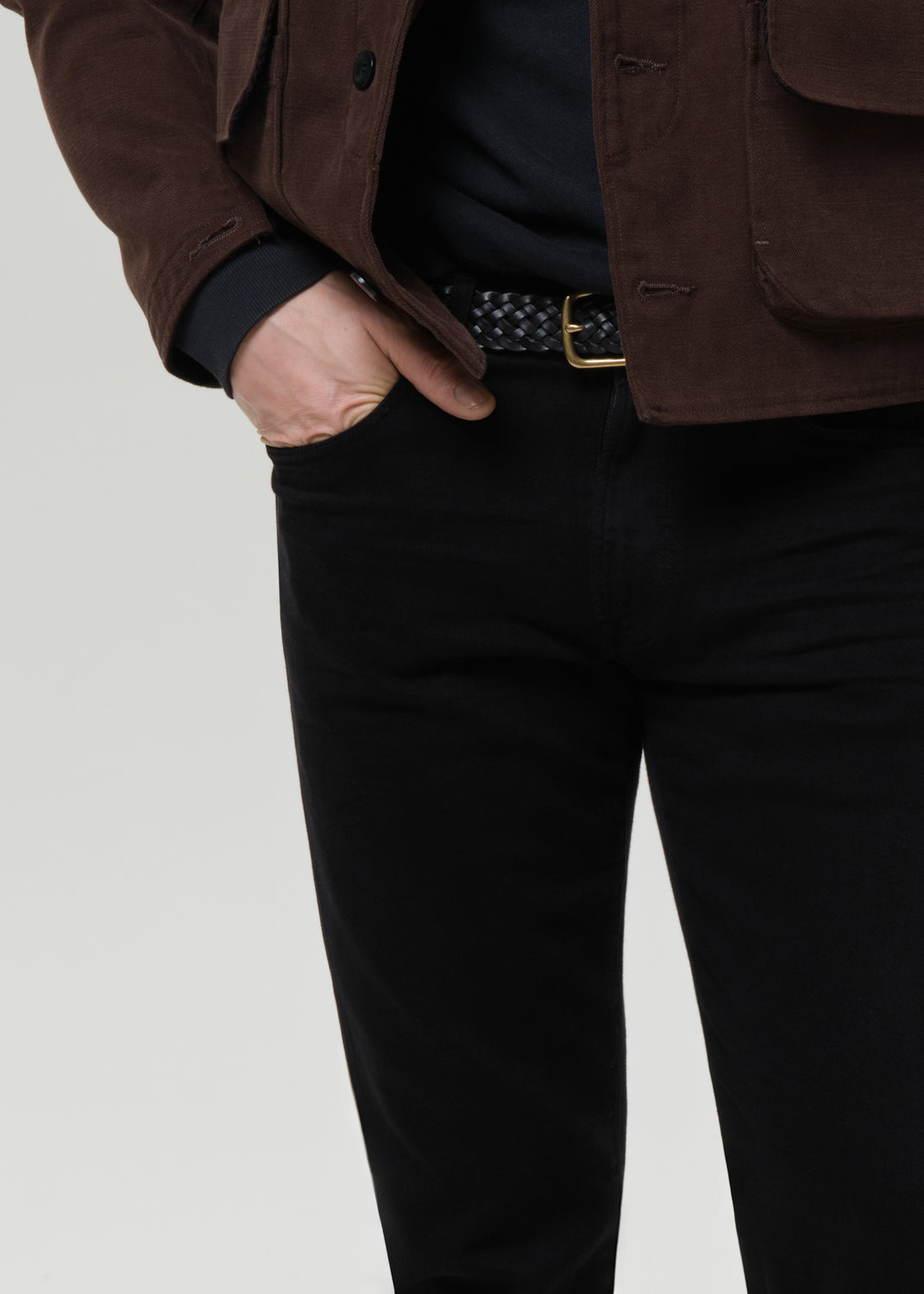 Close-up of black straight leg jeans on a grey background.