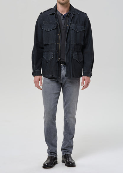Person wearing light grey straight leg jeans with a black denim jacket and black crewneck tee on a grey background.