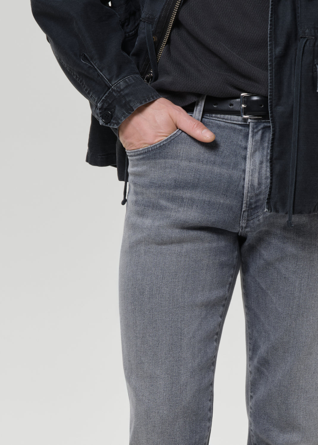 Close-up of light grey straight leg jeans on a grey background.