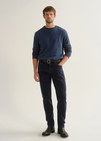 Person wearing dark navy pants, a blue long sleeve shirt, and black boots, front full body view on a light grey background.