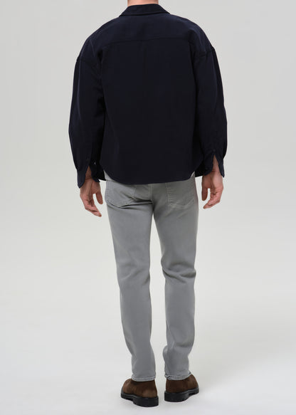 Person wearing a dark shirt and grey pants on a grey background