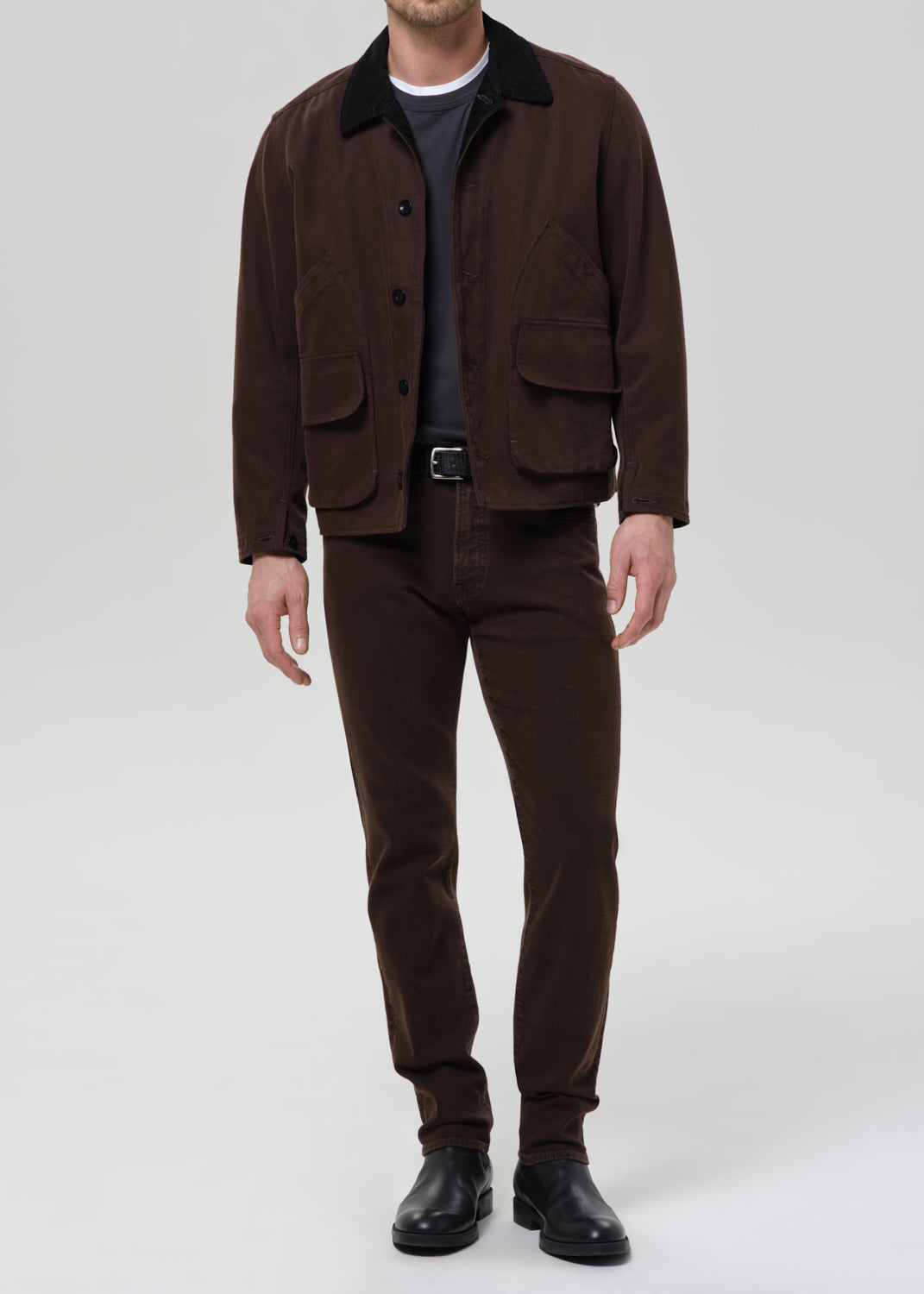 Man wearing a brown jacket and pants on a grey background