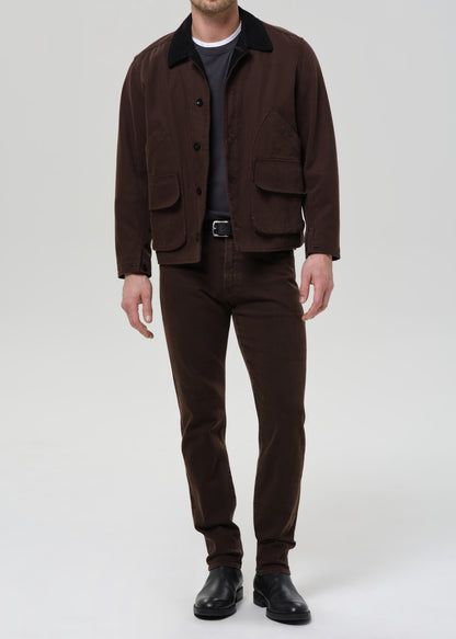 Man wearing a brown jacket and pants on a grey background