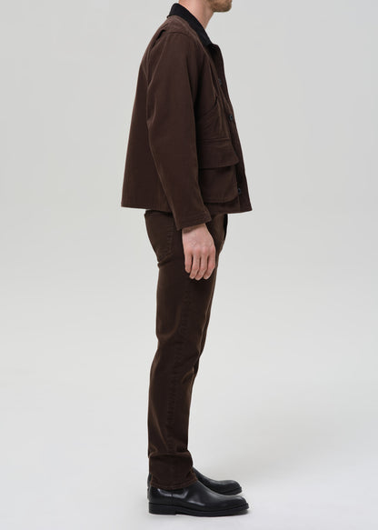 Person wearing a brown jacket and pants on a grey background