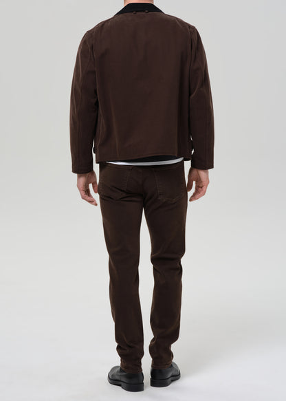 Person wearing a brown jacket and pants on a grey background