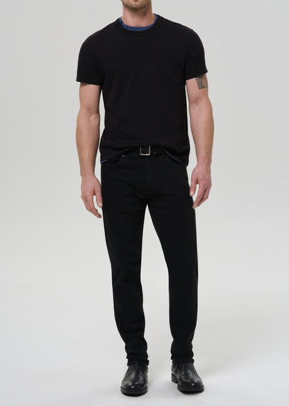 Man wearing a black t-shirt and black pants on a grey background