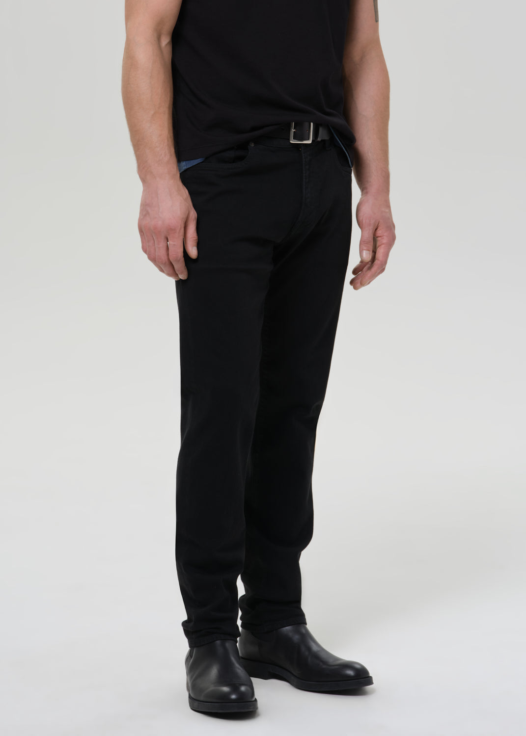 Person wearing black pants and black shoes on a grey background