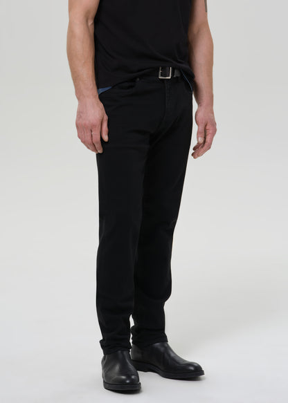 Person wearing black pants and black shoes on a grey background
