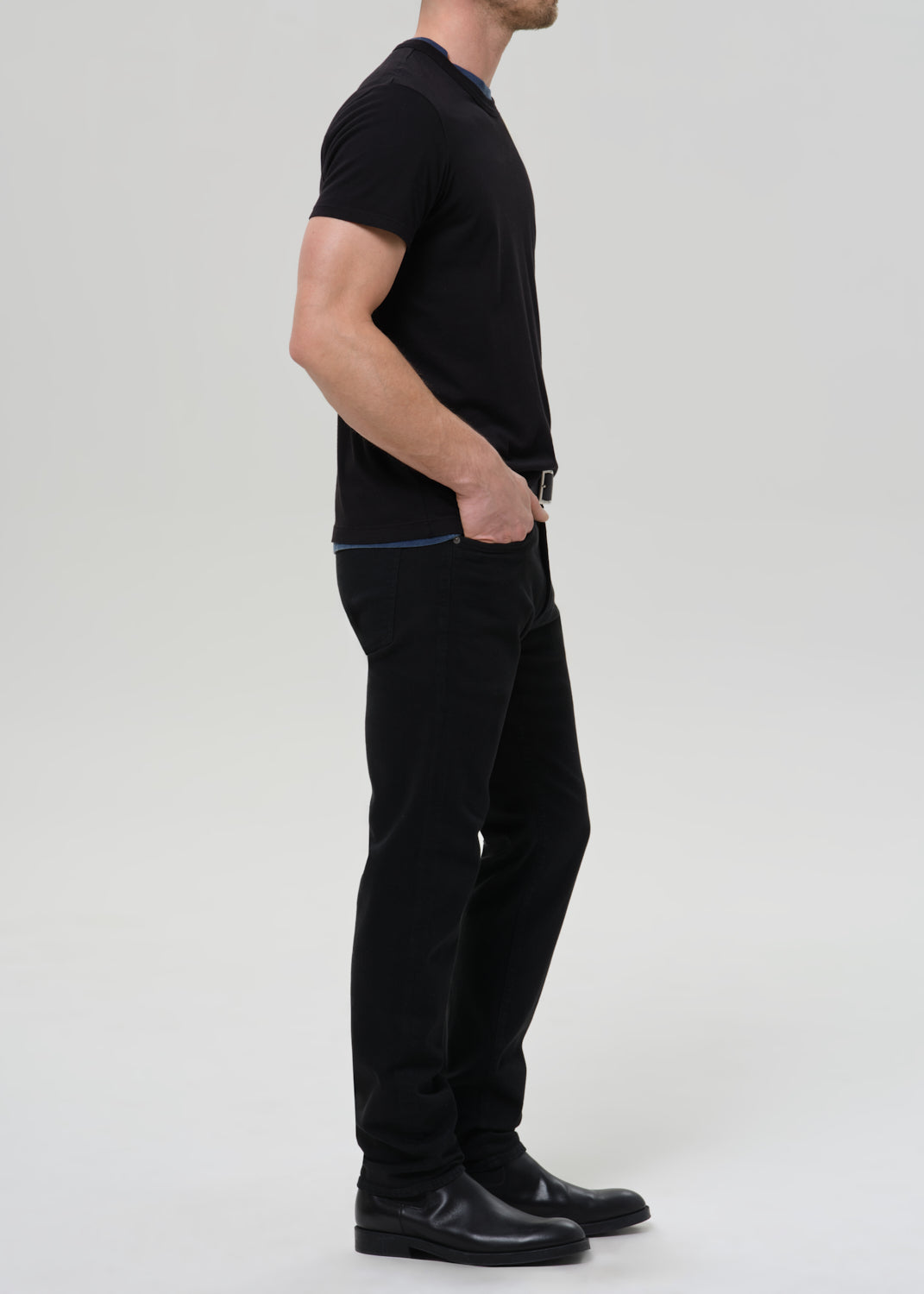 Person wearing a black t-shirt and black pants on a grey background