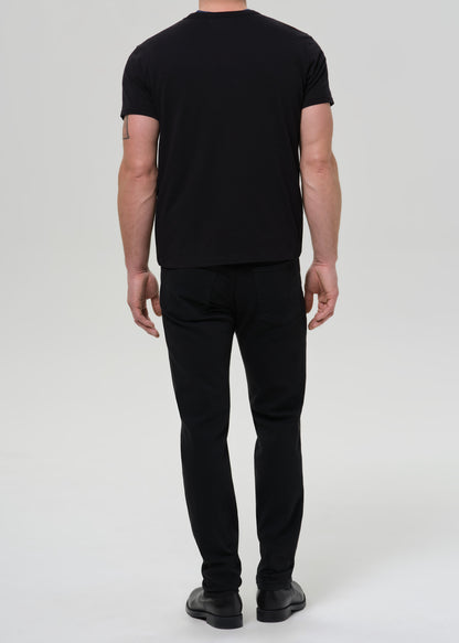 Person wearing a black t-shirt and black pants on a grey background