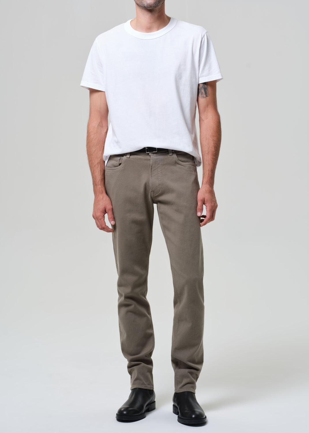 Person wearing a white t-shirt and olive pants on a plain background