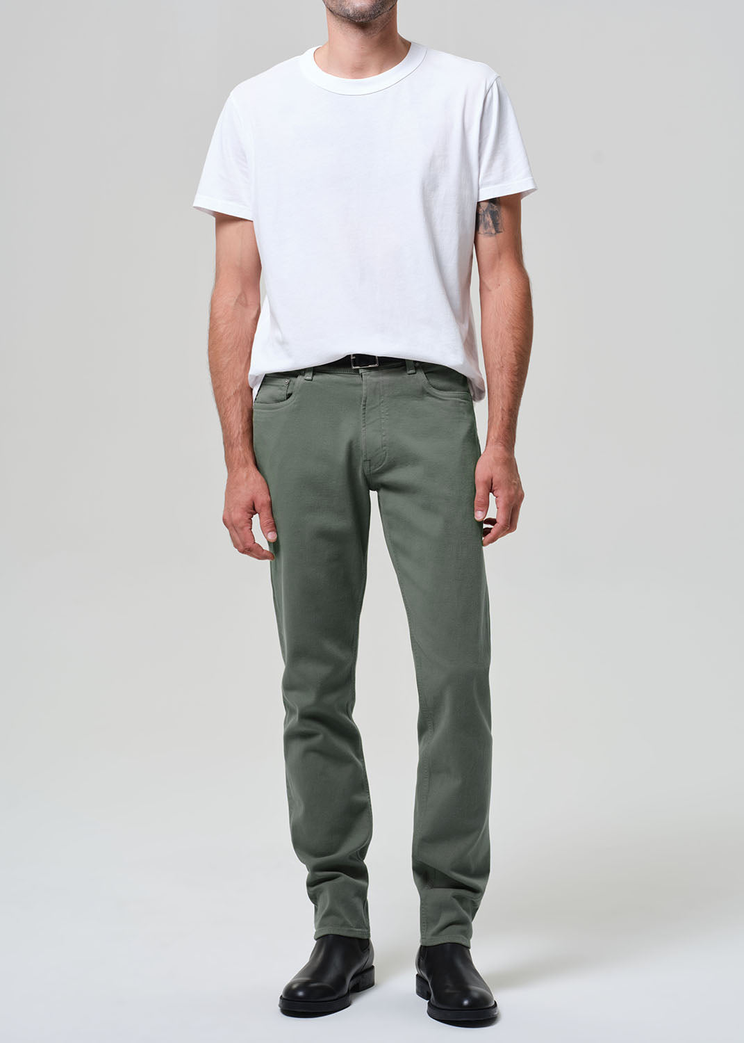 Person wearing a white t-shirt and green pants on a plain background