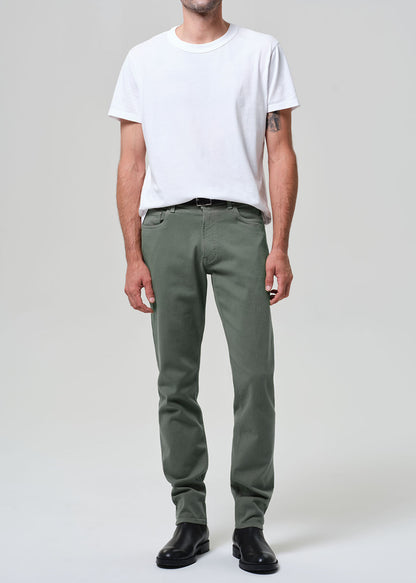 Person wearing a white t-shirt and green pants on a plain background
