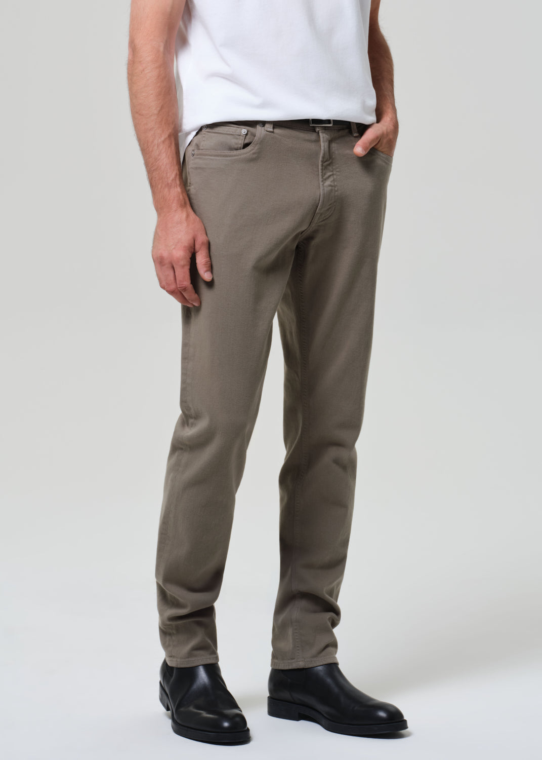 Person wearing a white t-shirt and olive pants on a plain background