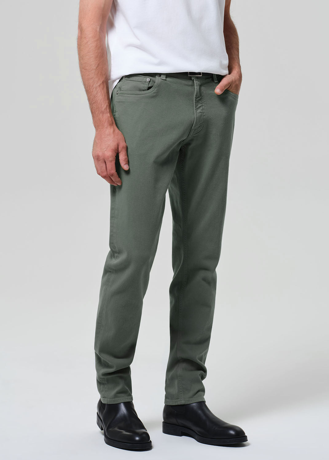 Person wearing green pants and black shoes on a plain background