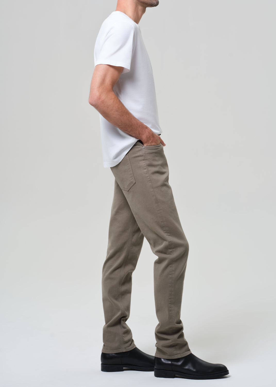 Person wearing a white t-shirt and olive pants on a plain background