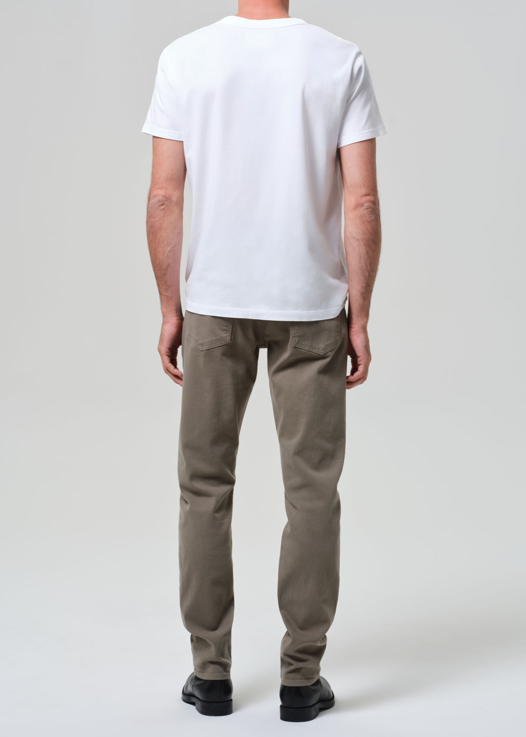 Person wearing a white t-shirt and olive pants on a plain background