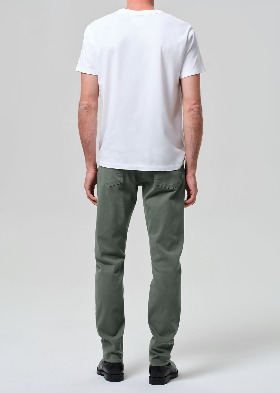Person wearing a white t-shirt and green pants on a plain background