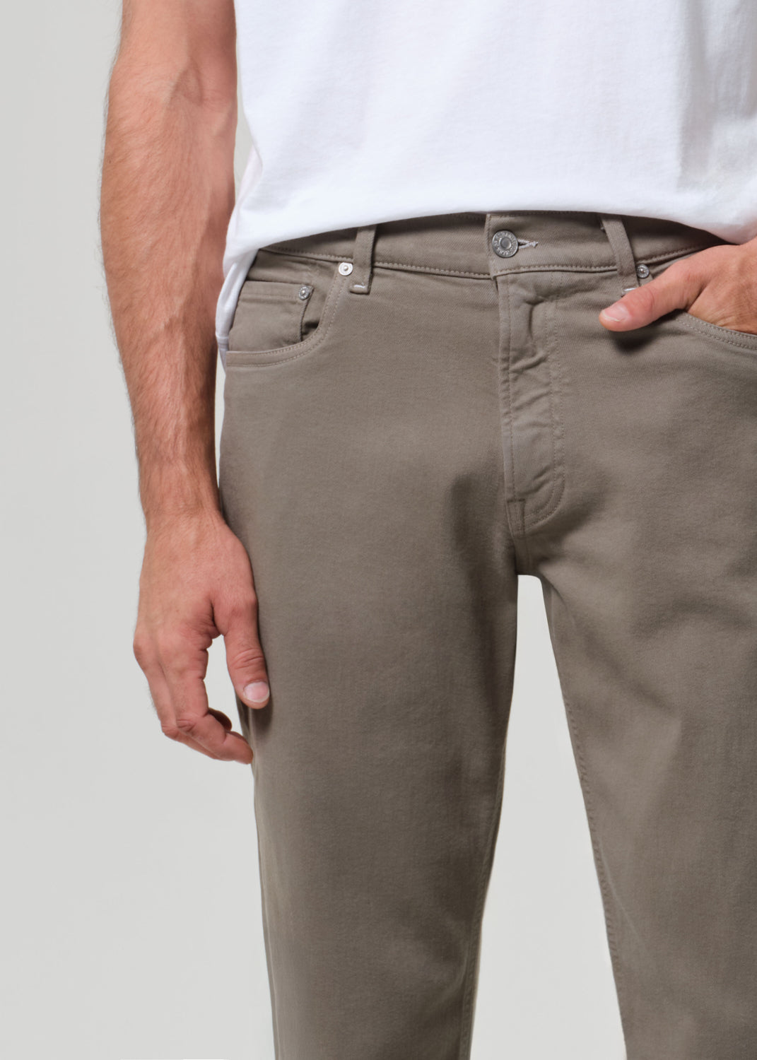 Person wearing a white t-shirt and olive pants on a plain background