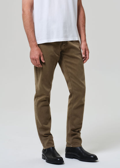 Person wearing brown pants and black shoes on a grey background