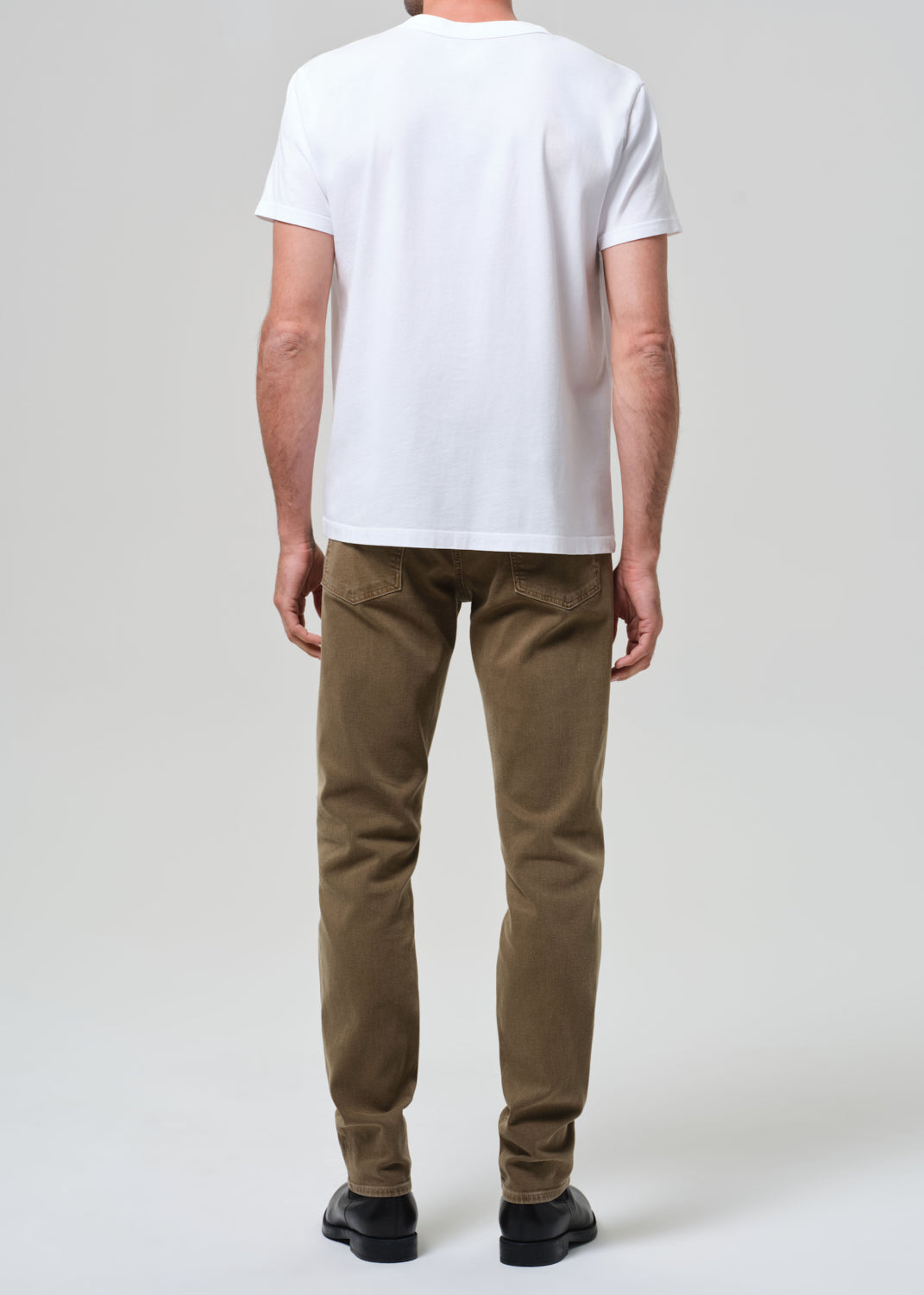 Person wearing a white t-shirt and brown pants on a plain background