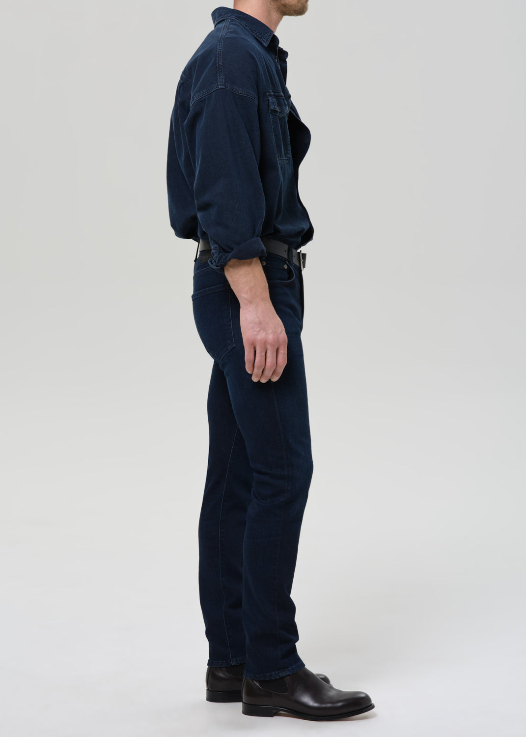 Person wearing a dark blue shirt and blue jeans on a grey background