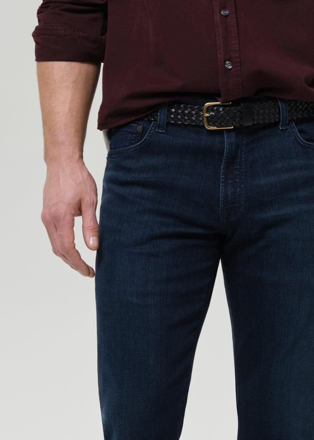 Close-up of dark indigo straight leg jeans on a grey background.
